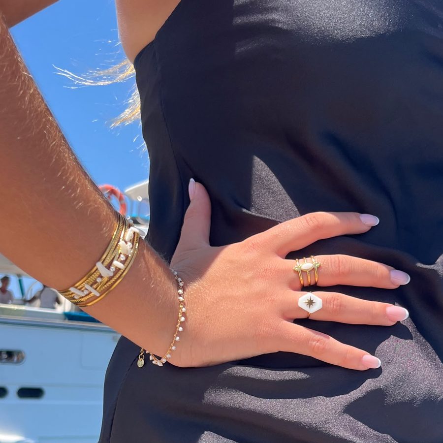 Pulseras y anillos dorados con los barcos del puerto detrás